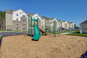 New Bern apartment for rent - A playground with a green slide in front of apartment buildings.