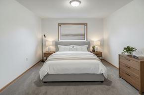 Stambaugh apartment for rent - A bedroom with a large bed, two lamps, and a nightstand with a plant on it.