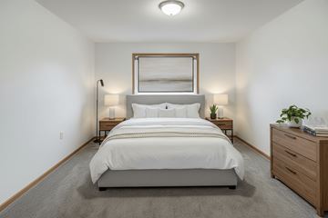 Stambaugh apartment for rent - A bedroom with a large bed, two lamps, and a nightstand with a plant on it.