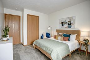 Paulding apartment for rent - A bedroom with a bed, nightstand, and two doors.