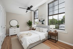 Columbus apartment for rent - A bedroom with a large bed, a ceiling fan, and a window with a view of the outside.