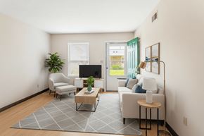 Dickson apartment for rent - A living room with a grey rug, a white sofa, a wooden coffee table, a grey chair, a green plant, a flat screen TV, and a picture frame on the wall.