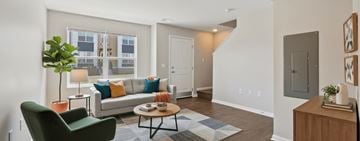 Pontiac apartment for rent - A living room with a green chair and a couch with pillows.
