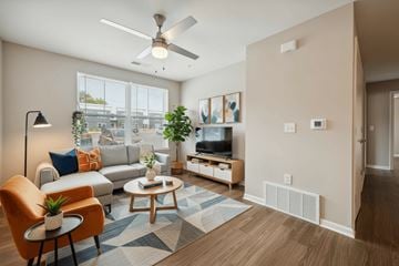 East Lansing apartment for rent - A living room with a brown chair and a blue rug.