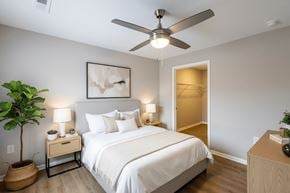 Zanesville apartment for rent - A bedroom with a large bed, a ceiling fan, and a plant.