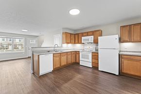 Noblesville apartment for rent - an empty kitchen with wooden cabinets and white appliances