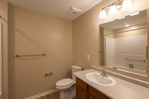 Columbus apartment for rent - A bathroom with a toilet, sink, mirror, and a towel bar.