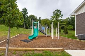 Lancaster apartment for rent - A playground with a green slide and a brown surface.