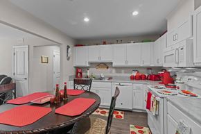 Greenville apartment for rent - a kitchen with white cabinets and a table with red chairs