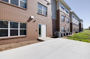 Indianola apartment for rent - a walkway leading to a brick building with a white door