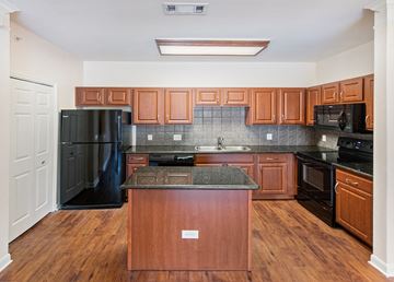 Austin apartment for rent - A kitchen with wooden cabinets and black appliances.