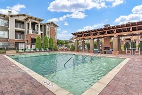 Austin apartment for rent - A large swimming pool in front of a building with a covered patio area.