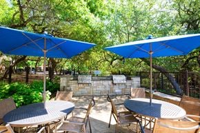 Austin apartment for rent - A patio with a table and chairs under blue umbrellas.