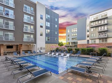 Austin apartment for rent - A swimming pool surrounded by lounge chairs in front of apartment buildings.