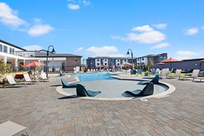 Mcdonough apartment for rent - a large swimming pool with lounge chairs and umbrellas in front of a building