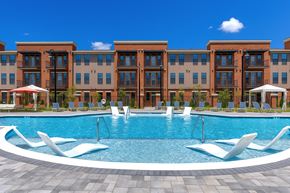 Madison apartment for rent - A large swimming pool in front of a building with lounge chairs around it.
