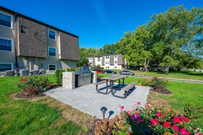 Huntington apartment for rent - a patio with a picnic table and a grill in front of an apartment building