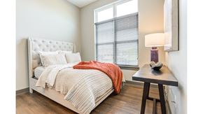 Carmel apartment for rent - A bedroom with a bed, a side table with a lamp, and a window with blinds.