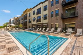 Carmel apartment for rent - A pool surrounded by lounge chairs in front of a building.