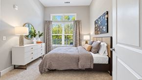 Lawrenceville apartment for rent - Furnished apartment bedroom with gray bedding, a white dresser and patterned curtains at Argento at Sugarloaf.