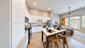 Mcdonough apartment for rent - A2 one-bedroom apartment kitchen with white cabinets, stainless steel appliances, and a dining table at Argento at the Bridges in McDonough, GA.