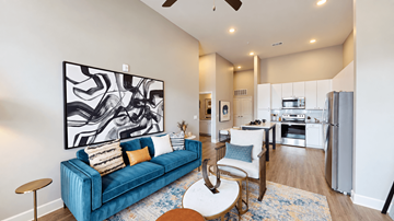 Mcdonough apartment for rent - A living room with a blue couch and a large abstract painting on the wall.