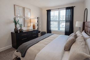 Arden apartment for rent - A bedroom with a large bed and a window with black curtains.