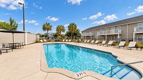 Myrtle Beach apartment for rent - Outdoor swimming pool with entry steps, lounge chairs and palm trees at Canterbury Apartments in Myrtle Beach, SC.