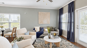 Indian Land apartment for rent - A living room with a white sofa, a wooden chair, a white coffee table, and a painting on the wall.