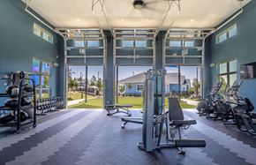 Kannapolis apartment for rent - brand new fitness center features free weights, medicine balls and slam balls. There are three garage doors opening to to the plush green yoga lawn. Bikes and other machines are also present. The ceiling has a large fan and the walls are a calming tone of greenish blue.