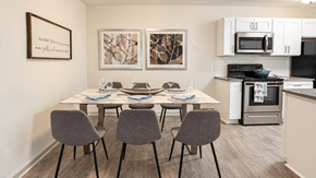 Decatur apartment for rent - Dining table with six chairs beside a kitchen with white cabinets at Icon Avondale Apartments in Decatur, GA.