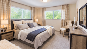 Decatur apartment for rent - Furnished bedroom with two windows, bedside lamps, a dresser and an accent chair at Icon Avondale Apartments in Decatur, GA.