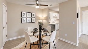Cartersville apartment for rent - Dining area with a round glass table, four chairs, and a view into the kitchen at Icon Cartersville Apartments.