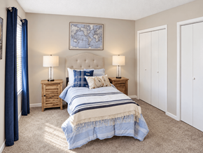 Birmingham townhouse for rent - Bedroom with carpet, closet storage, and blue-accented furnishings at Madison Park Apartments & Townhomes in Birmingham, AL.