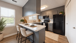 Birmingham townhouse for rent - Apartment kitchen with gray cabinetry, breakfast peninsula, black appliances, and wood-style flooring at Madison Park in Birmingham, AL.