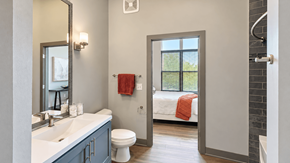 Carmel apartment for rent - Bathroom with a white vanity countertop, gray cabinetry and a doorway to the bedroom at VER at Proscenium in Carmel, IN.