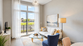 Carmel apartment for rent - Furnished living room with a sofa, blue accent chair and glass doors to a balcony at VER at Proscenium in Carmel, IN.