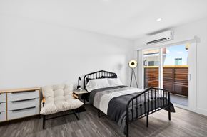 Los Angeles apartment for rent - A bedroom with a black metal bed and a white chair with a wooden frame.