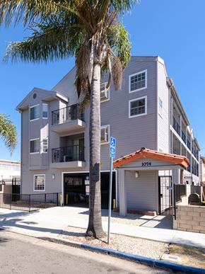 Long Beach apartment for rent - A palm tree stands in front of a two-story building with a garage.