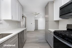Los Angeles apartment for rent - A kitchen with white cabinets and a black stove top oven.