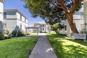 Los Angeles apartment for rent - a walkway between two buildings with a tree and a bench