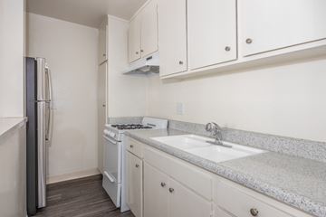 Van Nuys apartment for rent - a kitchen with white cabinets and a sink and a refrigerator