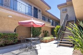 Van Nuys apartment for rent - a patio with a table and chairs and an umbrella in front of a building