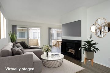 Los Angeles apartment for rent - A living room with a grey couch, a black fireplace, and a television mounted on the wall.