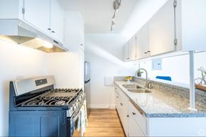 Sherman Oaks apartment for rent - A kitchen with a blue stove and white cabinets.