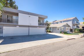Long Beach apartment for rent - A white two-story apartment building with a garage door and balcony.