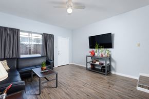 Long Beach apartment for rent - A living room with a black couch, a glass coffee table, and a flat screen TV mounted on the wall.