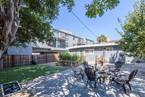 Long Beach apartment for rent - A patio with a table and chairs is surrounded by a fence and trees.