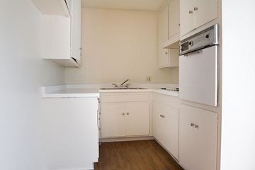 North Hollywood apartment for rent - an empty kitchen with white cabinets and a stove and refrigerator