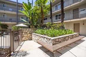 Los Angeles apartment for rent - a stone retaining wall with a wooden bench in front of an apartment building